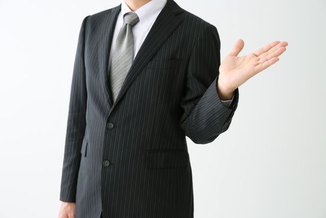 左手の平を上に向けるスーツの男性